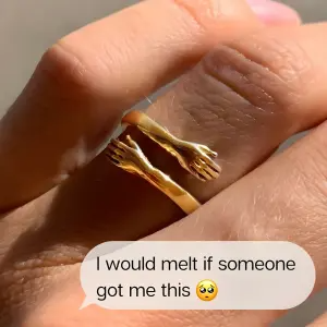 fake text message bubble overlaid on a close-up photo of a hugging-arms gold ring