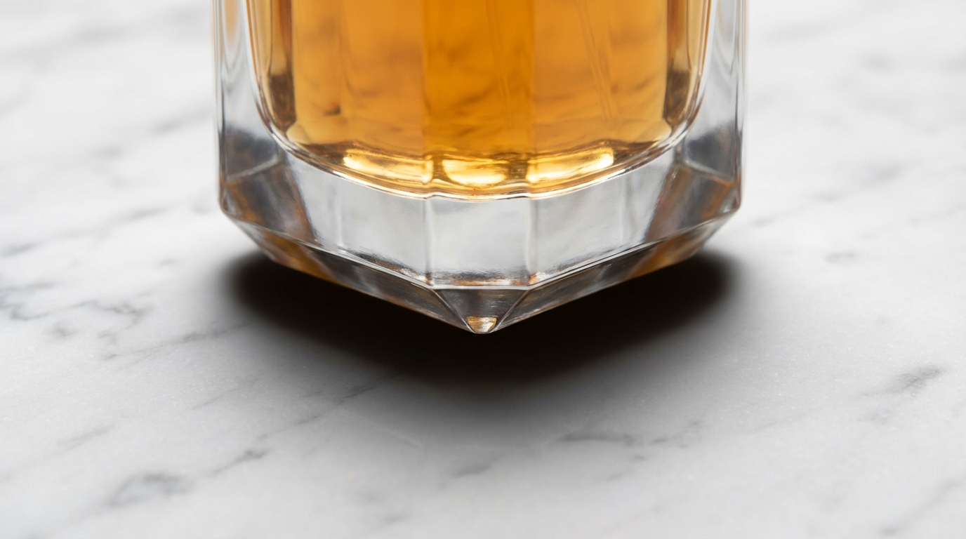 Close-up of a glass bottle base on marble with a dense dark contact shadow at the point of contact