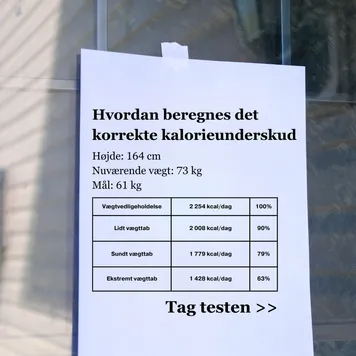 printed paper flyer taped to a glass window showing a calorie deficit table and a take the test call to action