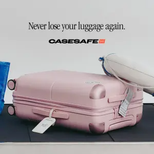 Pink hardshell suitcase with a smart tracking tag on an airport baggage carousel under the headline 'Never lose your luggage again.'